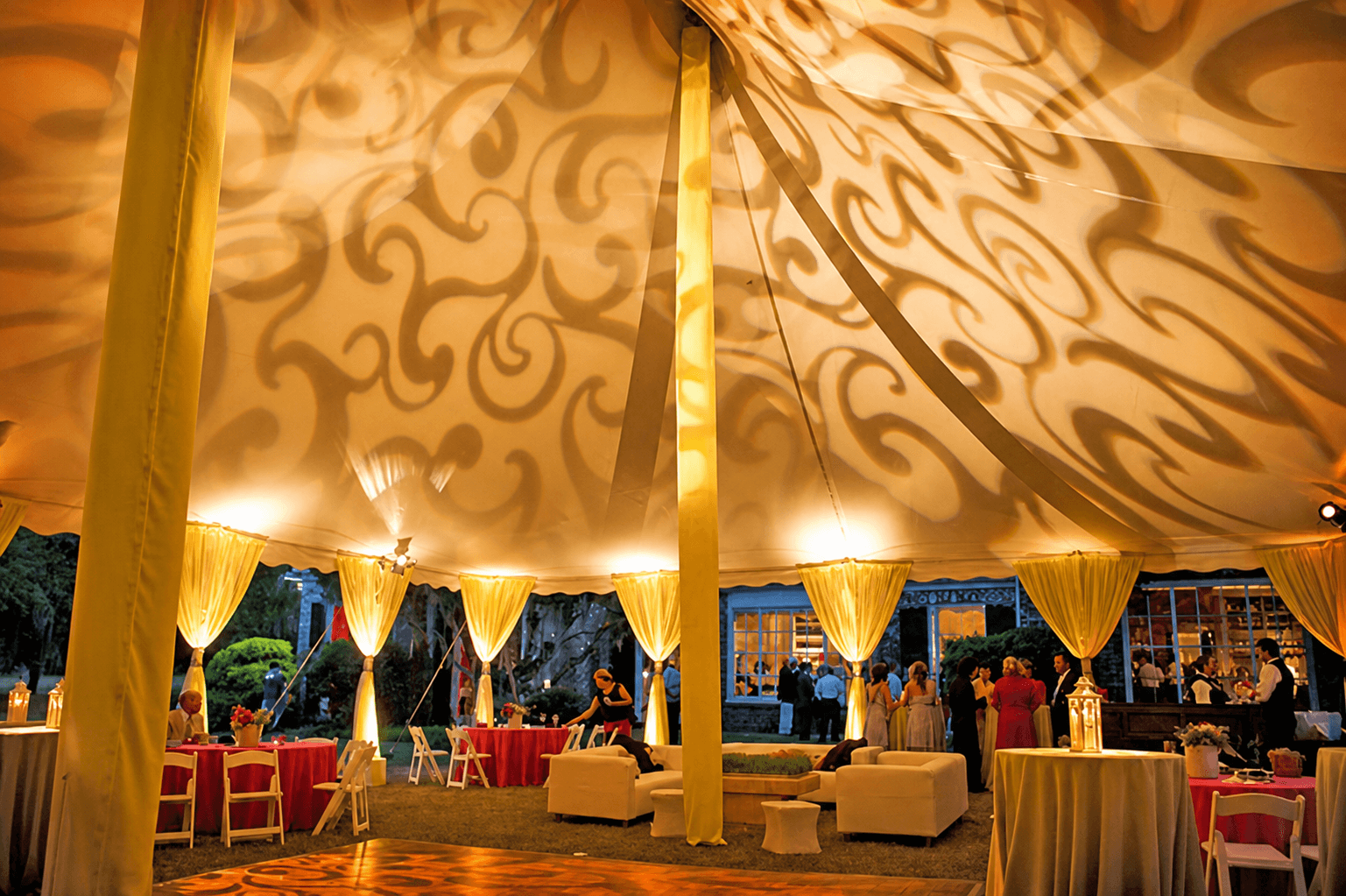 Warm GOBO lighting projected across a tented evening event.
